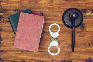 Judge gavel, law books and handcuffs on a wooden background